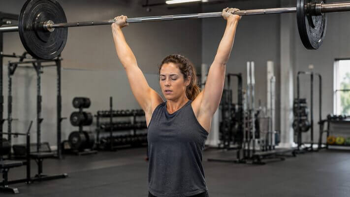 Athlete experiencing brief dizziness at the top of an overhead press set