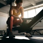Person pausing on a rowing machine with mild stomach discomfort after exercise