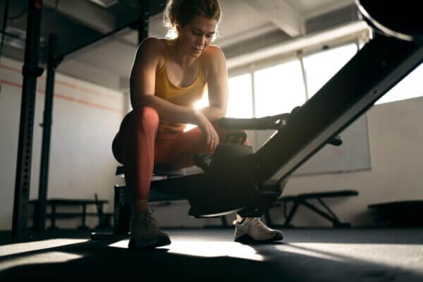Person pausing on a rowing machine with mild stomach discomfort after exercise