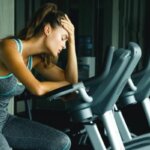 Woman experiencing headache after spin class in indoor cycling studio