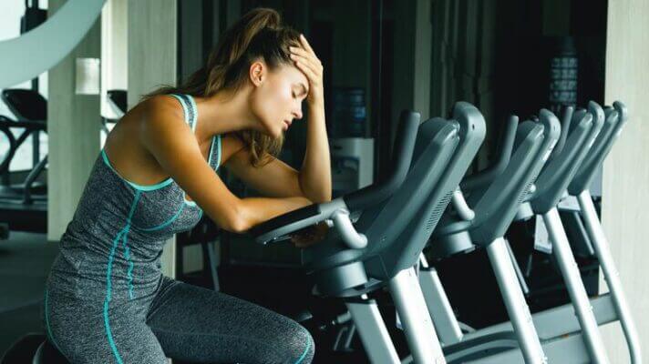Woman experiencing headache after spin class in indoor cycling studio