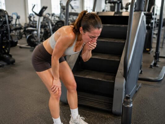Woman feeling nauseous while using a StairMaster machine at the gym