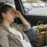 Person feeling tired after grocery shopping and unpacking groceries at home