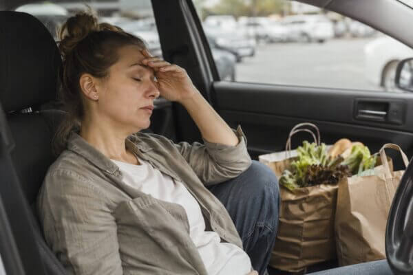 Person feeling tired after grocery shopping and unpacking groceries at home