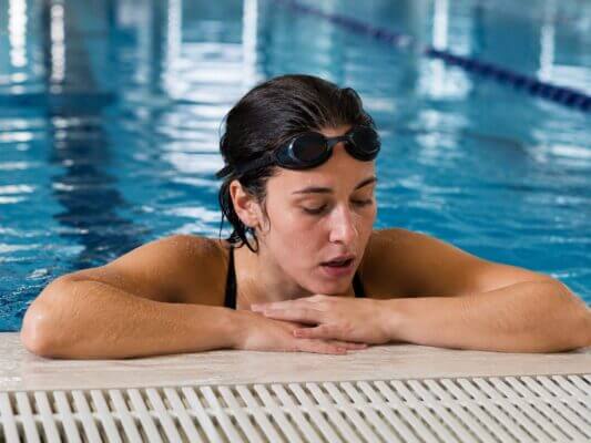 Swimmer resting at the edge of an indoor pool after a hard swim workout