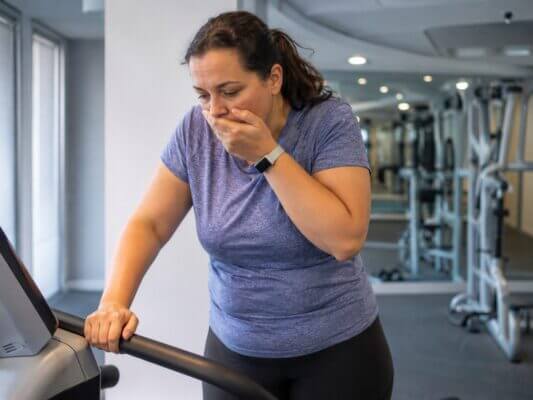 Person feeling nauseous while walking on a treadmill in a gym