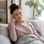 Person sitting up after a nap and feeling slightly dizzy in a bright living room